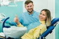 Beautiful girl patient shows the class with her hand while sitting in the Dentist`s chair Royalty Free Stock Photo