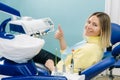 Beautiful girl patient shows the class with her hand while sitting in the Dentist& x27;s chair Royalty Free Stock Photo