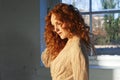 Beautiful girl in pensive pose with long wavy red hair highlighted in sun light Royalty Free Stock Photo