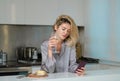 Beautiful girl with phone drinking wine in kitchen. Morning of pretty woman housewife. Royalty Free Stock Photo