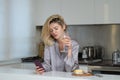 Beautiful girl with phone drinking wine in kitchen. Morning of pretty woman housewife. Royalty Free Stock Photo