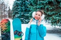 Beautiful girl on the phone, happy smiling in winter park on the background of trees and snowboards. Talking over the Royalty Free Stock Photo