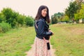 Beautiful smiling girl with a phone on her belt looks back while standing in the middle of a green park Royalty Free Stock Photo