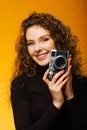 Beautiful girl with photo camera isolated on yellow background Royalty Free Stock Photo