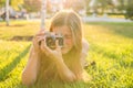 Beautiful girl photographer holds a camera and lying on the grass in the spring outdoors in the park. The concept of Royalty Free Stock Photo