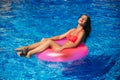 A beautiful girl in a pink bathing suit sunbathing by the pool. Sunny weather. Summer. Royalty Free Stock Photo