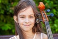 Beautiful girl in a pink dress with a cello in the village