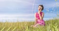 Beautiful girl in pink dress sits on green lawn against blue sky and talks on phone. Royalty Free Stock Photo