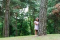 A beautiful girl in a pink dress stands near a tree in the forest and dreams Royalty Free Stock Photo