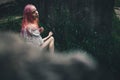 The beautiful girl with pink hair sits on the thrown ladder in an environment of a green grass Royalty Free Stock Photo