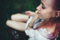 The beautiful girl with pink hair sits on the thrown ladder in an environment of a green grass Royalty Free Stock Photo