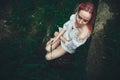 The beautiful girl with pink hair sits on the thrown ladder in an environment of a green grass Royalty Free Stock Photo