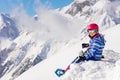 Cute ski girl portrait sit in snow on mountain top Royalty Free Stock Photo