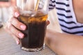 Beautiful girl with a pink manicure holds and drinking a large glass with soda with pieces of ice and a straw on a sunny hot day. Royalty Free Stock Photo