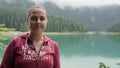 Beautiful girl in a pink sweatshirt on a background of blue, green lake in Montenegro