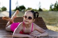 A beautiful girl in a pink swimsuit and glasses is lying on a sunbed on the sea Royalty Free Stock Photo