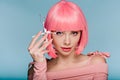 Beautiful girl in pink wig posing with scissors isolated