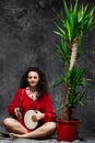 Beautiful girl playing drum in tropical plants over grey background. Royalty Free Stock Photo