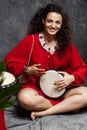 Beautiful girl playing drum in tropical plants over grey background. Royalty Free Stock Photo