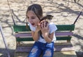 A beautiful girl is playing with a kitten, sitting on a homemade antique swing. A cute teenage girl screams with joy. A cute