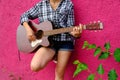 Beautiful girl plays the acoustic guitar. Guitarist on a pink background. Handsome young acoustic guitar blues player Royalty Free Stock Photo