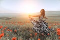 beautiful girl in a poppy field at sunset.