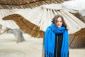 Portrait of young beautiful and cute girl in black coat and blue scarf outdoors on the cold weather with reed sunshades in the bac