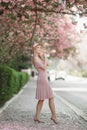 Beautiful girl posing in The Pink peach and Sakura Flowers Blooming Garden. Young attractive woman smiling, posing Royalty Free Stock Photo