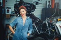 Beautiful girl posing repairs a motorcycle in a workshop, pin-up style, service and sale Royalty Free Stock Photo