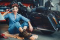 Beautiful girl posing repairs a motorcycle in a workshop, pin-up style, service and sale Royalty Free Stock Photo