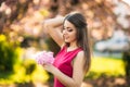 Beautiful girl posing to the photographer against the background of blooming pink trees. Spring. Sakura.