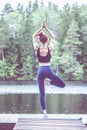 Beautiful girl  practicing yoga Tree pose, Vrikshasana   on the lake.  The concept of appeasement,  healthy lifestyle Royalty Free Stock Photo