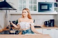 Beautiful girl prepares food on an induction stove. A woman cooks soup or sauce in a saucepan. The blonde in the bright kitchen