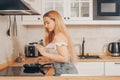 Beautiful girl prepares food on an induction stove. A woman prepares breakfast in a frying pan. The blonde in the bright kitchen