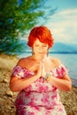 Beautiful girl with radiant red hair in sommer dress in a meditative spiritual gesture of prayer.