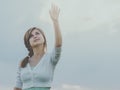 Beautiful girl raised her hand up to the sky and clouds, the concept of purity, beauty, religion, spirituality