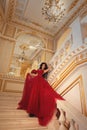 Beautiful girl in a red ball gown in palace interiors Royalty Free Stock Photo