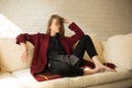 Beautiful girl in a red coat having a rest on the sofa Royalty Free Stock Photo