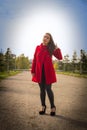 Beautiful girl in a red coat on a park alley Royalty Free Stock Photo