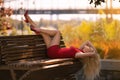 Beautiful girl in the red dress with perfect legs posing outdoor in the city park