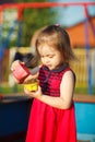 Beautiful girl red dress plays in sandbox. child safety on the playground. Royalty Free Stock Photo