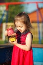 Beautiful girl red dress plays in sandbox. child safety on the playground. Royalty Free Stock Photo