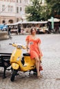 Beautiful girl in red dress posing on city streets. Pretty brunette posing against building background. Stunning young woman Royalty Free Stock Photo