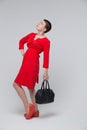Beautiful girl red dress posing in studio with bag Royalty Free Stock Photo