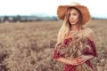 Beautiful girl red dress straw hat. In summer wheat field. Free space for text. Harvesting in village, wheat ears in Royalty Free Stock Photo