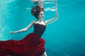 Beautiful girl in a red dress swims under water. amazing Underwater