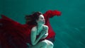 Beautiful girl in a red dress swims under water. amazing Underwater