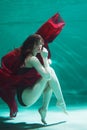 Beautiful girl in a red dress swims under water. amazing Underwater