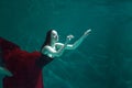 Beautiful girl in a red dress swims under water. amazing Underwater