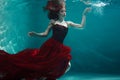 Beautiful girl in a red dress swims under water. amazing Underwater